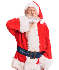 Old senior man with grey hair and long beard wearing traditional santa claus costume cutting throat with hand as knife, threaten aggression with furious violence