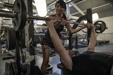 man exercising with dumbbell help by his coach	