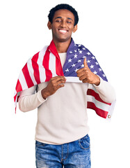 African handsome man holding united states flag smiling happy and positive, thumb up doing excellent and approval sign