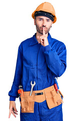 Young hispanic man wearing worker uniform asking to be quiet with finger on lips. silence and secret concept.
