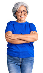 Senior woman with gray hair wearing casual clothes and glasses happy face smiling with crossed arms...