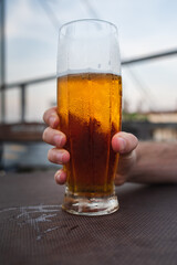 Close up of mans hand holding a glass full of beer