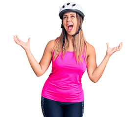 Obraz na płótnie Canvas Young beautiful woman wearing bike helmet crazy and mad shouting and yelling with aggressive expression and arms raised. frustration concept.