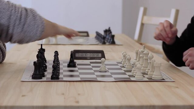 Chess players shake hands and start fast game. Two men plays in rapid chess on wooden table close up