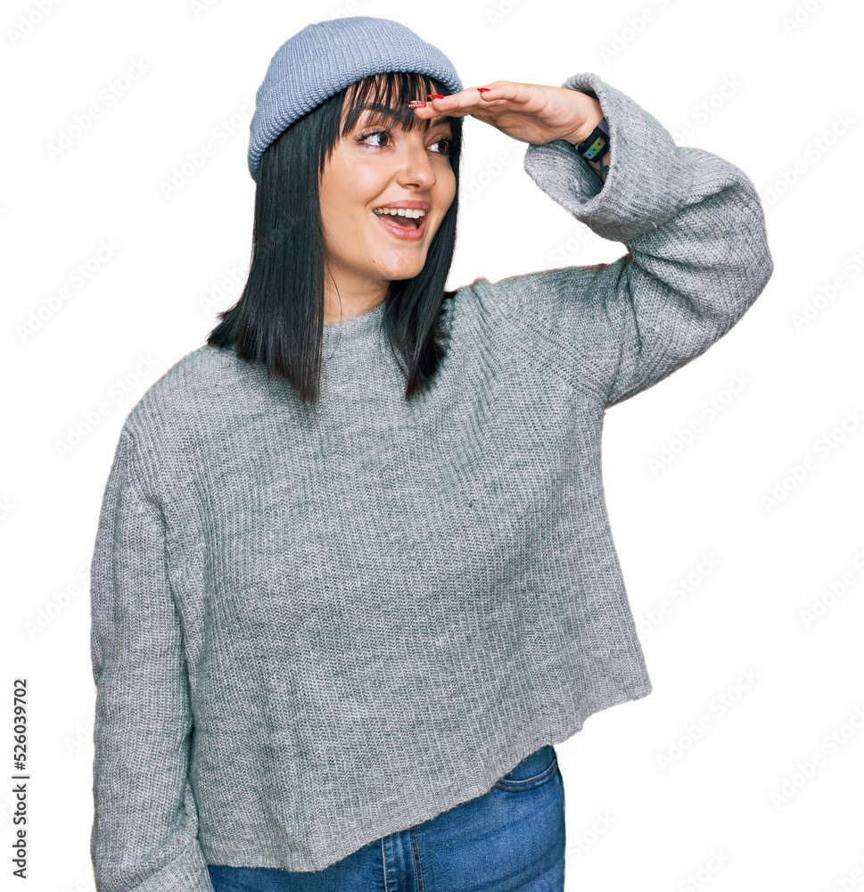 Canvas Prints Young hispanic woman wearing cute wool cap very happy and smiling looking far away with hand over head. searching concept.