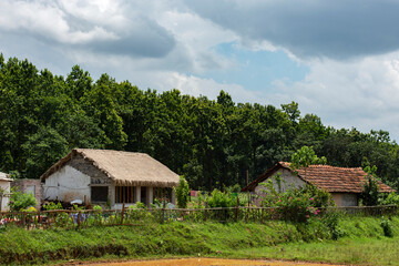 Fototapeta na wymiar A beautiful rural home of Jhargram West Bengal with flowers in foreground and blue sky and white clouds in background. Rural village house of India.
