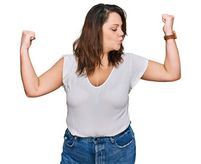 Young plus size woman wearing casual white t shirt showing arms muscles smiling proud. fitness...