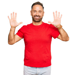 Handsome middle age man wearing casual red tshirt showing and pointing up with fingers number ten while smiling confident and happy.