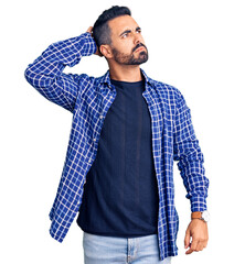 Young hispanic man wearing casual clothes confuse and wondering about question. uncertain with doubt, thinking with hand on head. pensive concept.