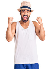 Young hispanic man wearing casual summer hat celebrating surprised and amazed for success with arms raised and open eyes. winner concept.