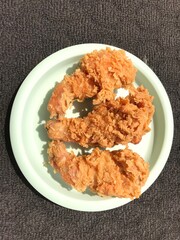 Floured fried chicken Photographed on a green plastic plate isolated on a dark background