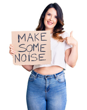 Beautiful young brunette woman holding make some noise banner pointing finger to one self smiling happy and proud