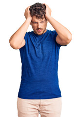 Young handsome man with curly hair wearing casual clothes suffering from headache desperate and stressed because pain and migraine. hands on head.