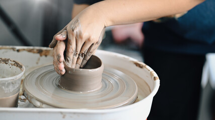 Close up view of female potter sculpting clay dishes on the pottery wheel in creative studio workshop. Activity, handicraft, hobbies concept