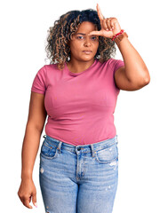 Young african american plus size woman wearing casual clothes making fun of people with fingers on forehead doing loser gesture mocking and insulting.