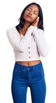 Young indian girl wearing casual clothes sleeping tired dreaming and posing with hands together while smiling with closed eyes.