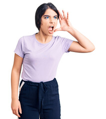 Obraz na płótnie Canvas Brunette teenager girl wearing casual clothes shouting and screaming loud to side with hand on mouth. communication concept.