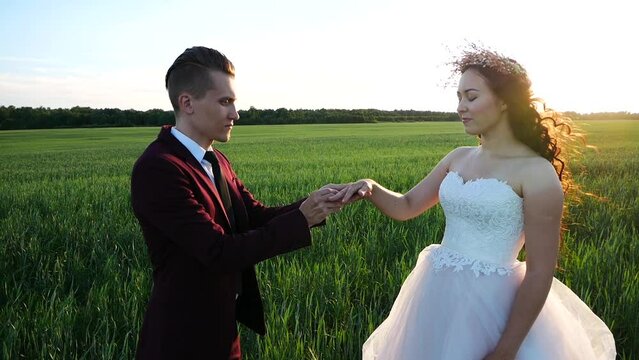 Groom proposes to bride for marriage. Guy puts ring on the bride's finger. But something went wrong and groom wears the ring incorrectly and they laugh about this situation.