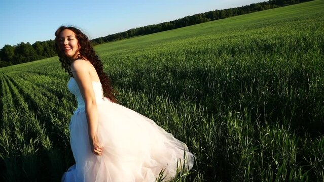 Bride throws her wreath aside and laughs and rejoices. The girl's wedding dress and hair sways in the wind.