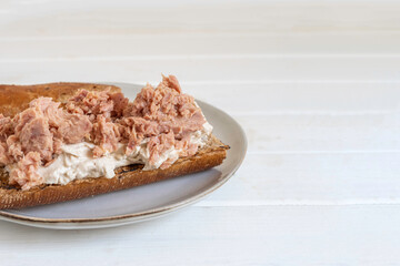 Tuna Hummus Sandwich on beige plate over wooden background with copy space.