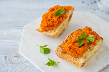 Appetizer or main course, open sandwiches with zucchini caviar on a ceramic board on a light wooden background. Zucchini recipes.