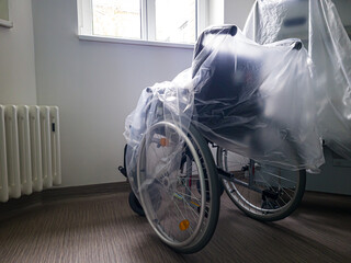 wheelchair. covered with foil. standing in the corridor of the hospital, clinic.