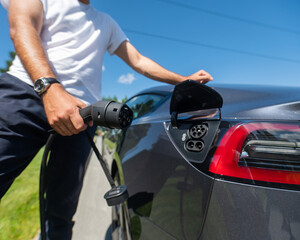 Caucasian man connect charger to electric car. 