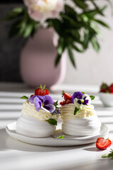 Fototapeta na wymiar Sweet pavlova's dessert decorated with fresh strawberry and flowers