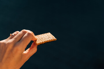 Hand with cracker outdoors on a sun light. Work snack for energy 