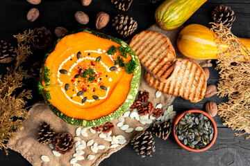 Pumpkin soup with pumpkin seeds, cream, parsley and spices on the rustic kitchen table. Flat lay. Top view
