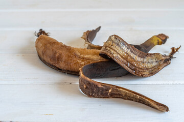 Rotten banana on white wooden background.