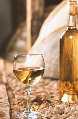 Wine bottle with White wine glass in a wine cellar