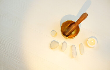 Tibetian singing bowl, candle and stones on white wooden background for sound therapy, with copy space, top view