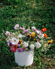 bunter Blumenstrauß, Strauß mit Blumen in einem rustikalen Behälter auf dem Feld