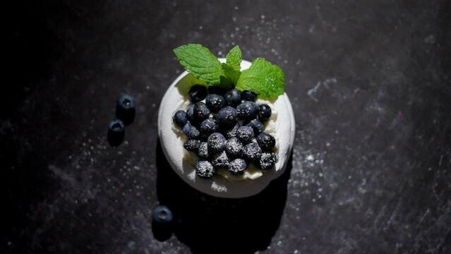 Mini meringue dessert pavlova cake with fresh blueberries plased on dark rusty table