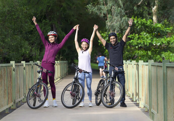 group of young friends ride bicycle on weekend, happy people cycling on walkway in the park