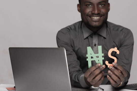 smiling black businessman holding dollar and naira sign