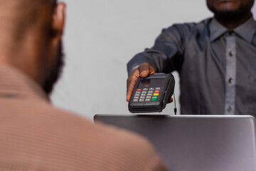 black businessman stretches a pos device to a customer