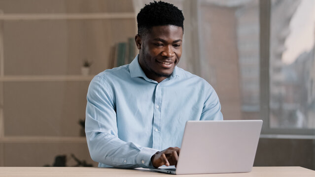 African american businessman professional worker male programmer man in blue shirt working freelance from home office typing email on laptop personal computer chatting searching internet job vacancy