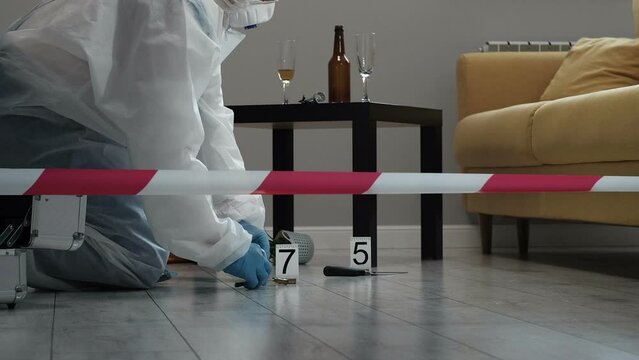 Forensic expert criminologist collects evidence at  crime scene, packaging of  fired cartridge case from  firearm, gloved hands close-up