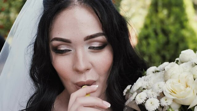 Portrait of a beautiful bride with a bouquet smoking an electronic cigarette and blowing smoke.IQOS