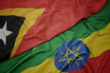 waving colorful flag of ethiopia and national flag of east timor.