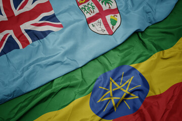 waving colorful flag of ethiopia and national flag of Fiji .