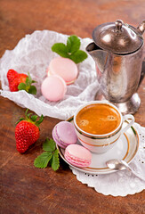 cup of coffee and macarons with strawberries on a wooden background