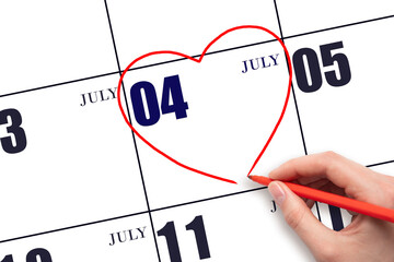 A woman's hand drawing a red heart shape on the calendar date of 4 July. Heart as a symbol of love.