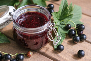 Homemade blackcurrants jam and fresh berries on a wooden background. Homemade preserving concept. Summer seasonal berry jams