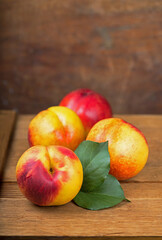 fresh nectarines with leaves on wooden background.