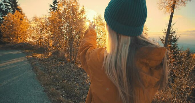 Happy Caucasian Woman enjoying, around nature, fall forest, tree. Concept follow me freedom. Female walking in woods in autumn day. Camel brown. Rusty red color. Grasses, plants, trees and parks.