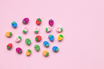 Colored wooden figures in the form of strawberries on a pink background