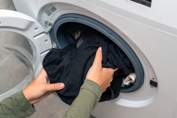 Young woman putting laundry in a washing machine